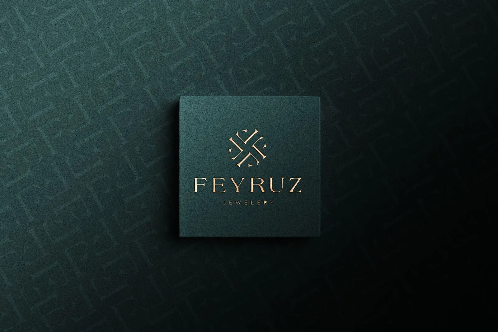Koyu petrol yeşili kart üzerinde bakır kabartma Feyruz Jewelery logosu, arka planda harflerden oluşan desen